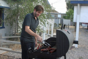 William Shattuck grills hot dogs and sausages.